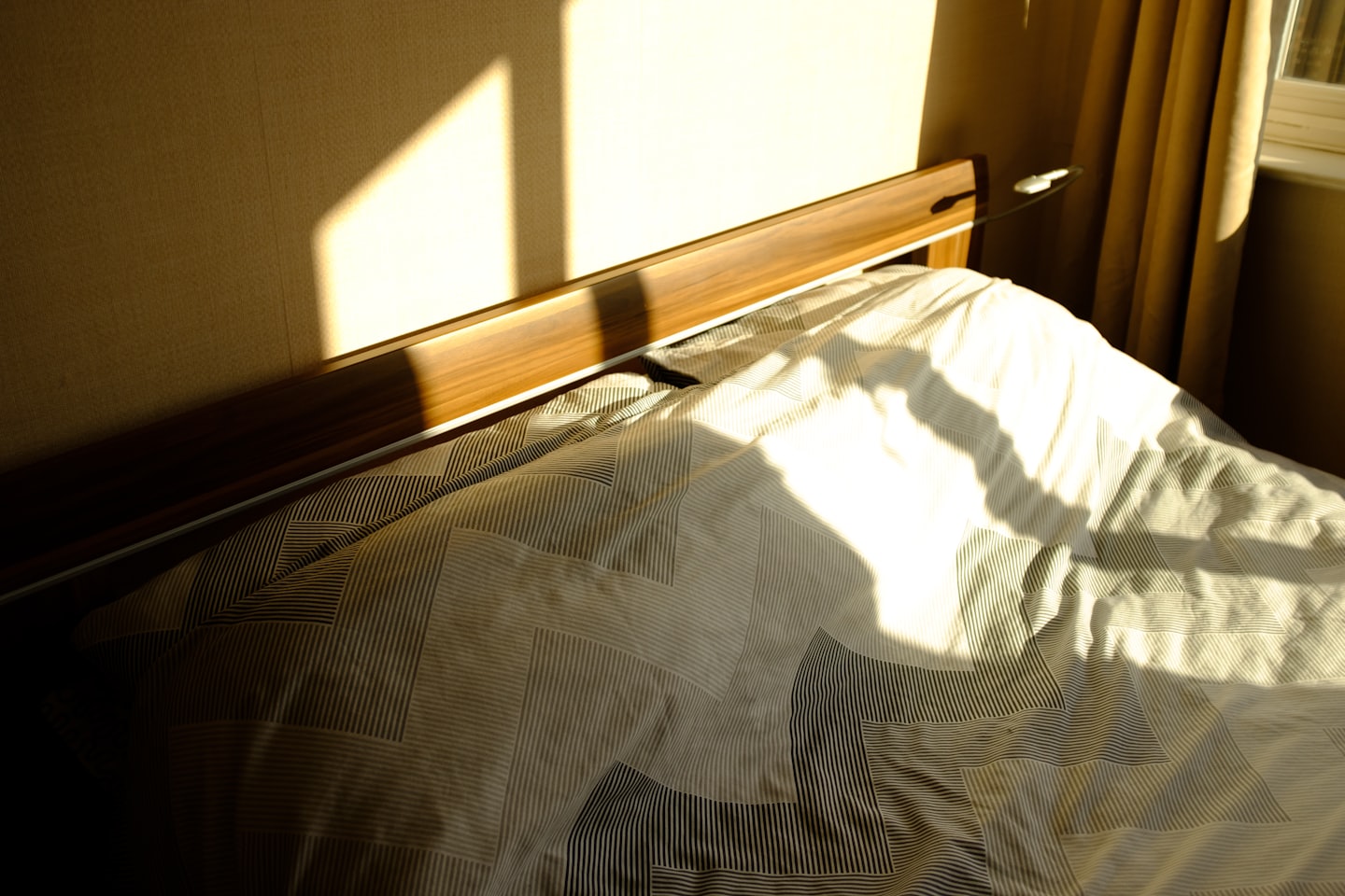 La luce del sole filtra su un letto con un copriletto fantasia.